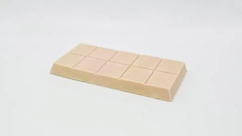  Light pink chocolate bar with segmented squares resting on white background Stock Photos