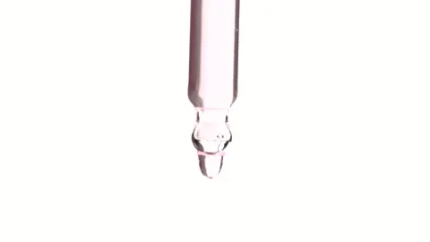 Light pink clear serum dripping from pipette in slow motion. Close up Stock Footage 294172936