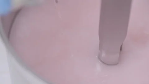 Light pink liquid mixture swirling around a rod in a container Stock Footage 340336060