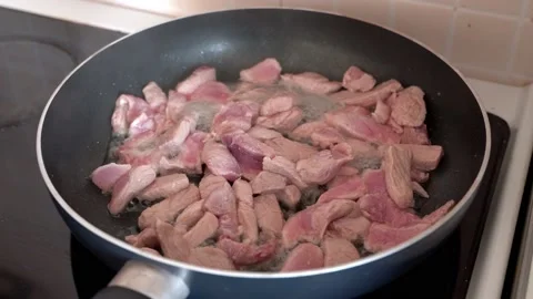 Light pink meat is fried in a frying pan with olive oil. Home cooking in the Stock Footage 183045895