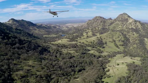 Light plane flying  in and around mountain range Stock Footage 240161213