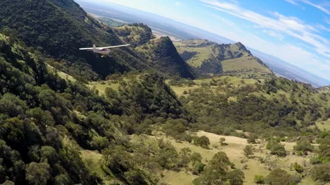 Light plane flying in mountain terrain Stock Footage 240161431