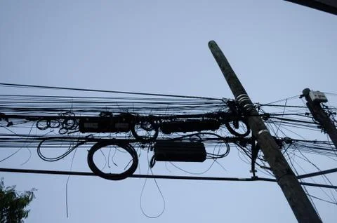 Light pole with many tangled cables, pattern of black cables on a wooden pole Stock Photos