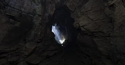 Light pours into a dark cavern revealing stunning rock formations Ilustración de archivo