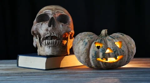 Light in pumpkin, skull and book on wooden background Stock-Footage 55639082