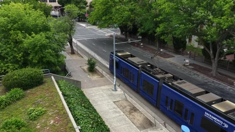 Light rail train moving through downtown Sacramento along quiet city street Vídeos de archivo 334659369