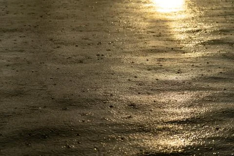 Light rain drops on water surface during sunset Stock Photos