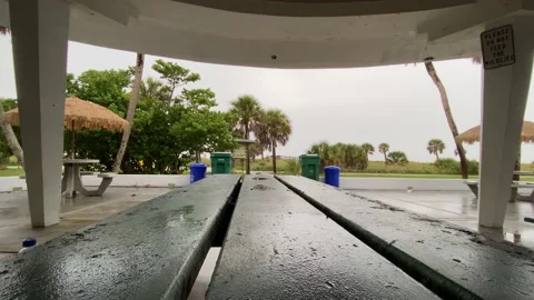 Light rain by empty picnic table by palm trees 動画素材 158842630