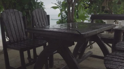 Light rain falls on a lonely table and chairs in outdoor cafe near the beach Stock Footage 87053288