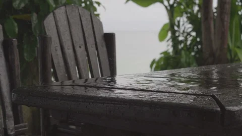 Light rain falls on a table and chair in outdoor cafe near the beach Stock Footage 87053770