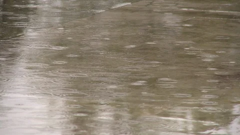 Light rain on sidewalk puddle in Lourdes, France, two pedestrians. Video stock 86758592