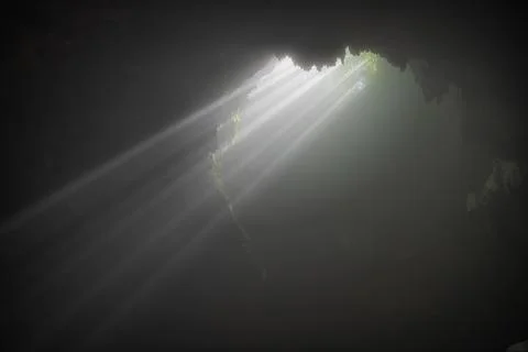 Light rays hitting limestone inside dark deep cave called Jomblang cave which Stock Photos