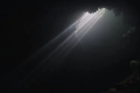 Light rays hitting limestone inside dark deep cave called Jomblang cave which Stock Photos