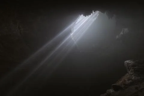 Light rays hitting limestone inside dark deep cave called Jomblang cave which Stock Photos