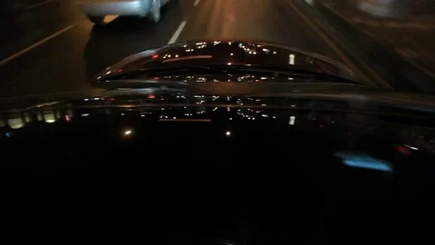 Late night drive through city with reflections of headlights