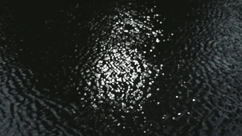 The light reflects on the surface of water in a dark setting, creating a series 스톡 동영상 344527435