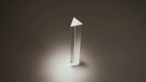 Light refracting through triangular glass prism, creating spectrum of colors and Stock Footage 311569602
