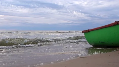 Light sea waves of surf roll the stern of a small wooden pleasure boat Stock Footage 197423552