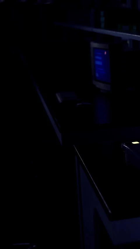 Light shines on desk in a dark room with screens and equipment in use Stock Footage 337956665