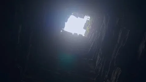 A light shines in end of a well-shape stone vertical tunnel in Ta Prohm temple Video stock 305672642