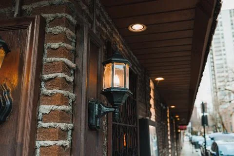 Light shines from a lantern on a wall of bricks. The lantern is fixed next to Фото