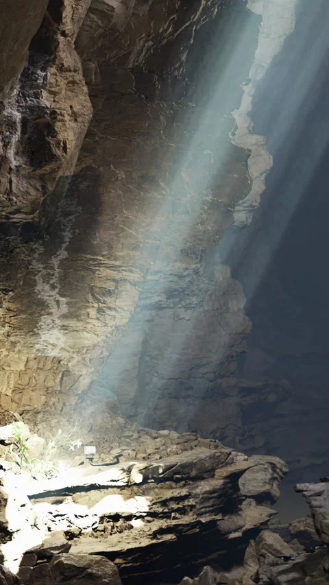 Light shines through cave opening at midday creating shadows on rocks Stock Footage 331753615
