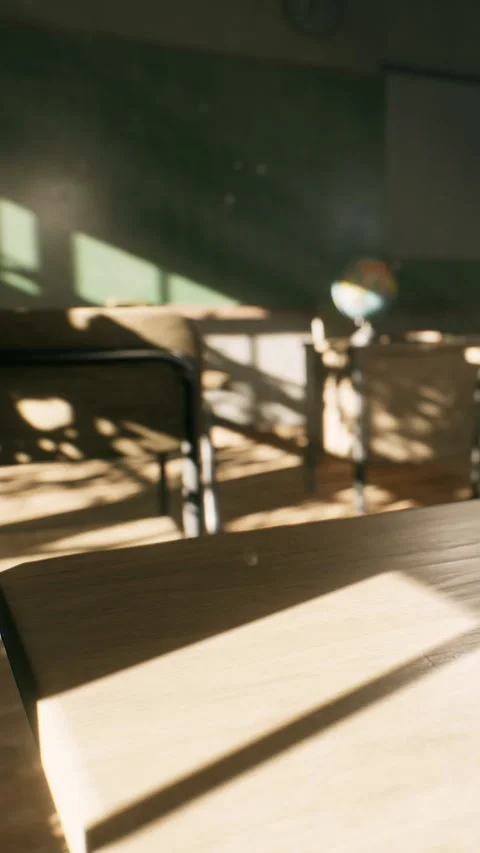 Light shines through a classroom with desks and a globe showing learning space Stock Footage 338427167