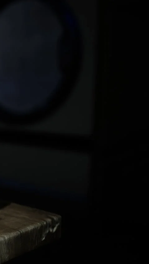 Light shines on a wooden surface in a dark room with a circular object Stock Footage 340636661