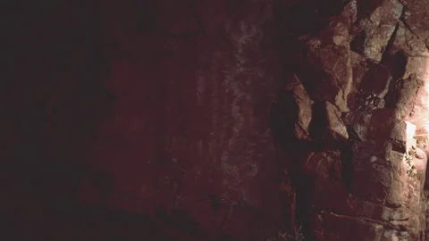 Light shining on a rock wall in a dark cave at night Stock Footage 344099742