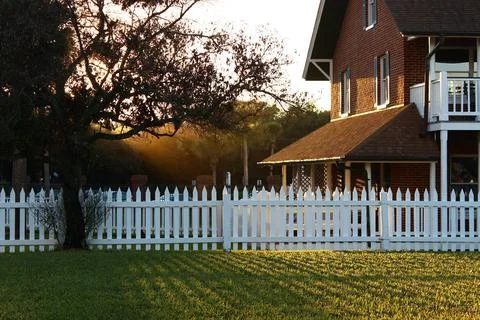 Light shining through the trees at sunset onto a beautiful brick home with .. Stock Photos