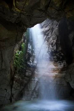 Light shining through waterfall in a an ancient cave Stock Photos