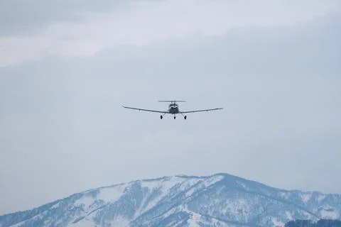 Light single-engine airplane climbing over snow-capped mountains Foto stock