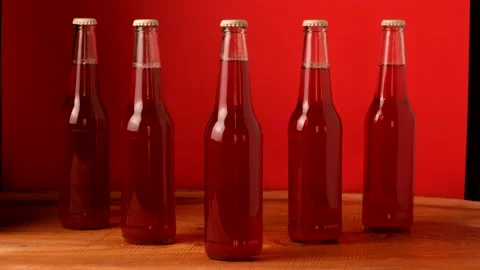 The light slowly turns on and illuminates five glass bottles on a red background 스톡 동영상 150686062