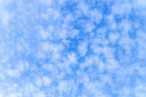 Light small cirrocumulus clouds on a sunny blue sky. Heavenly background. Stock Photos