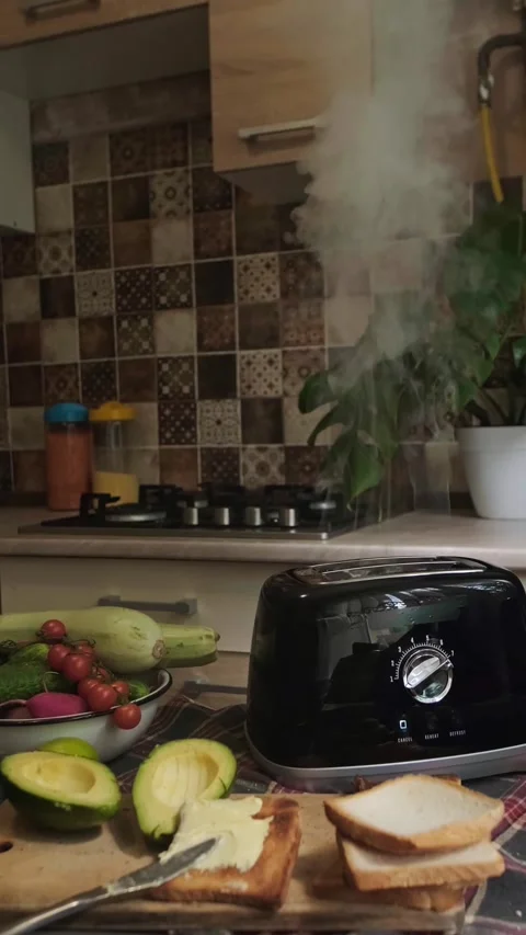 Light smoke rises from toaster after bread is toasted morning breakfast routine Stock Footage 311864380
