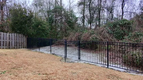 Light Snow Falling On A Back Yard While Crossing Over A Metal Gate Stock Footage 299711054