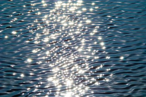 Light solid ripples on the sea water of pale blue color with glare from sunlight Foto stock