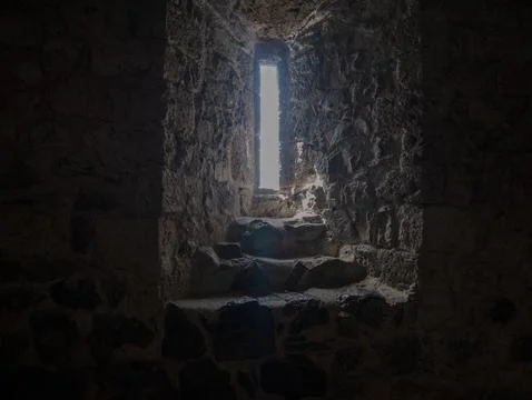 Light Streaming Through Barred Window in Old Stone Wall, Dungeon Atmosphere Stock-Fotos