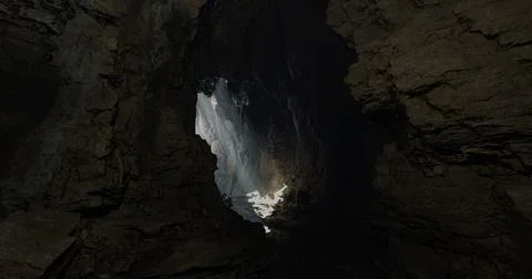 Light streaming through a cavern opening illuminates a rocky interior Stock Illustration