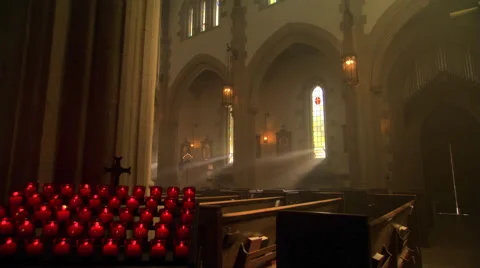 Light streaming through empty nave of Catholic church Stock Footage