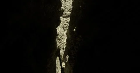 Light streaming through a narrow canyon crack in a rugged landscape Stock Illustration