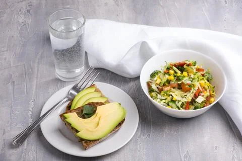 Light summer vegetable salad with corn and herbs and healthy avocado toast for Stock Photos