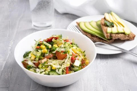 Light summer vegetable salad with corn and fresh herbs and healthy avocado toast Stock Photos