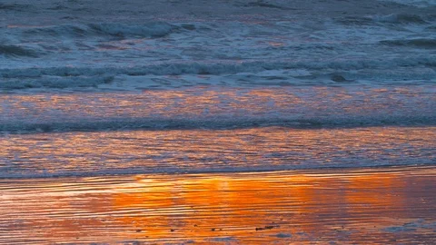 Light of the sunset and sky reflecting in the waves on the beach Stock Footage 124998008