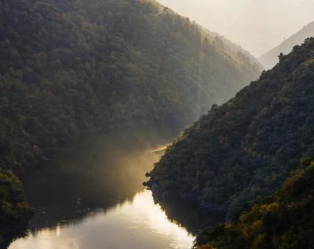 The light of the sunset is reflected in the calm waters of the Sil River Stock Photos