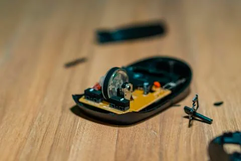 On the light surface of the desktop is a malfunctioning computer mouse without a Stock Photos