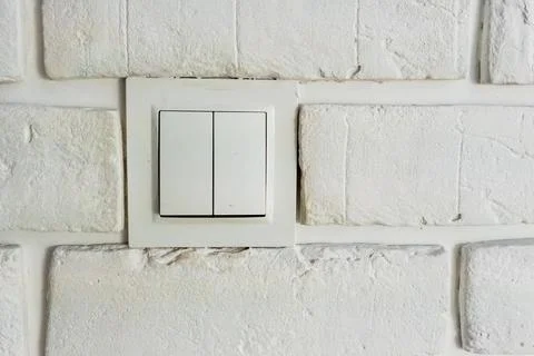 Light switch mounted on textured white brick wall, a modern element in Stock Photos