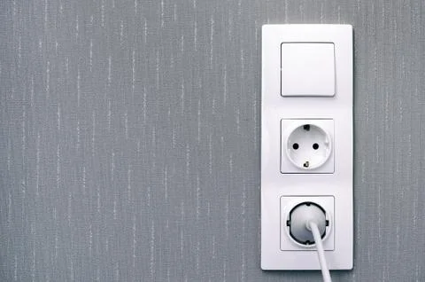 Light switch , power sockets, lead and plug on gray wall. Stock Photos