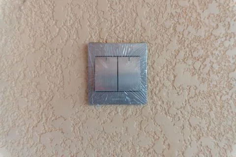 Light switch on a textured wall with protective plastic Stock Photos
