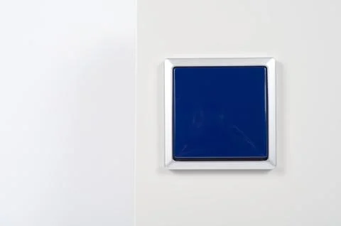 Light switch on the wall with blue button on silver frame Stock Photos